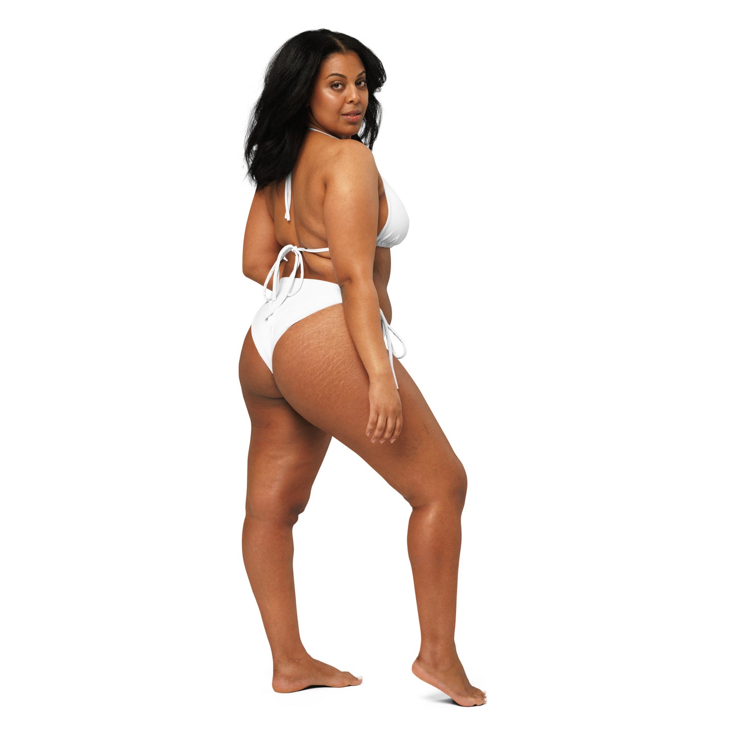 Seitliche Ganzkörperaufnahme des Modells im weißen Bikini „MAKI“ von POLCOUTURE vor neutralem weißem Hintergrund.