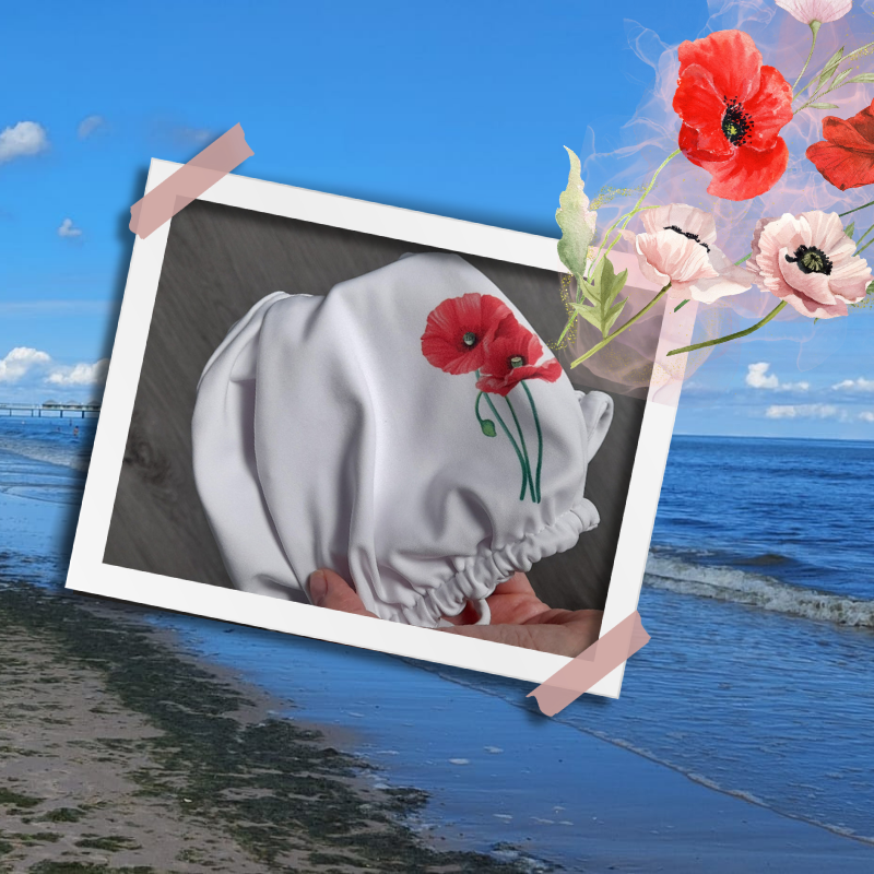 Foto: Ein Bikini mit einem Muster aus roten Mohnblumen (Maki). Im Hintergrund der Strand von Swinemünde.