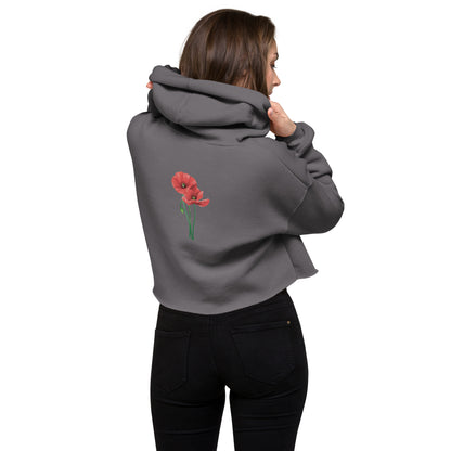 Rückansicht eines Models vor weißem Hintergrund, das den grauen Cropped Hoodie von POLCOUTURE trägt. Der Fokus liegt auf der lockeren Kapuze und dem modernen, kurzen Schnitt, der die Silhouette betont, sowie dem Mohnblumen Print.