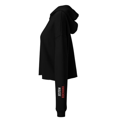 Seitenansicht des schwarzen Cropped Hoodies von POLCOUTURE. Der linke Ärmel zeigt den rot-weißen Print „Jestem kochana“.
