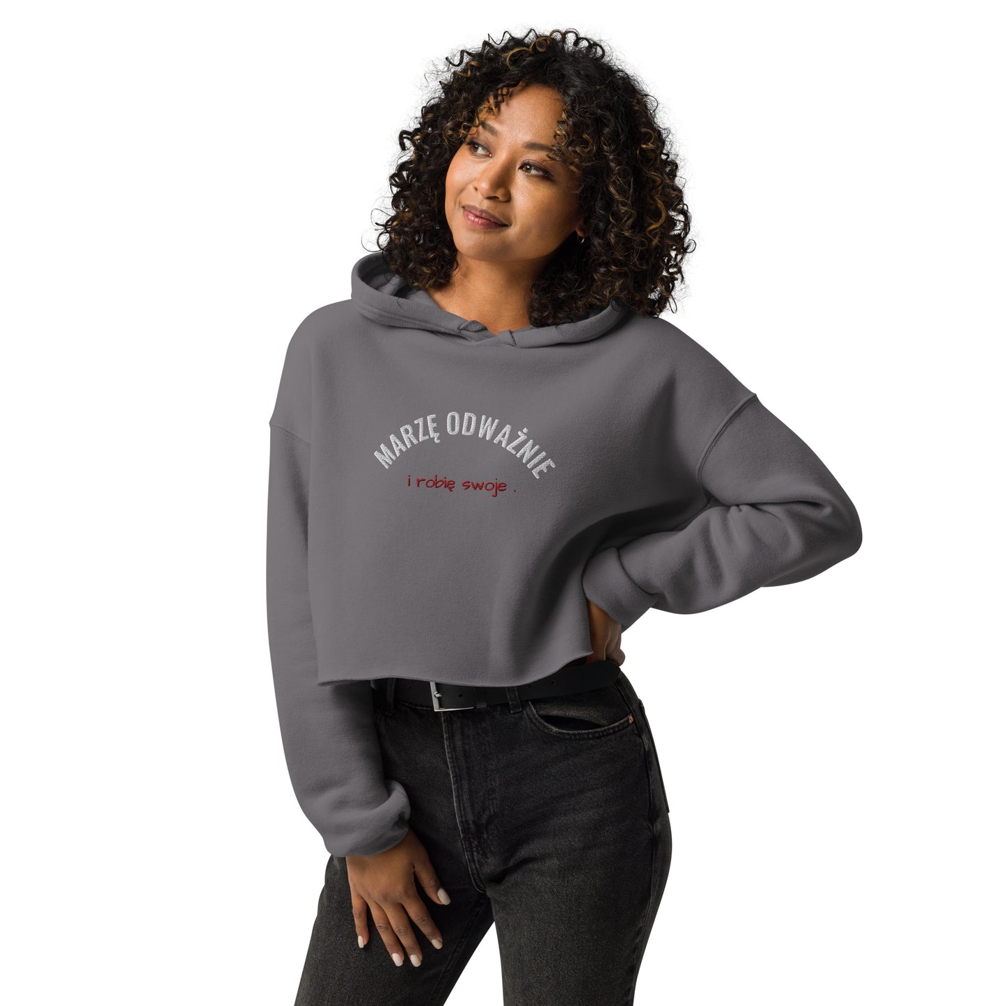 Ein Model präsentiert den grauen Cropped Hoodie von POLCOUTURE. Die Stickerei in Weiß und Rot setzt ein klares Statement auf dem modernen Kurz-Schnitt.