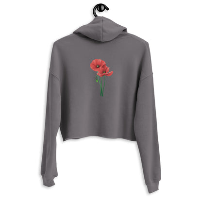 Die Rückansicht des grauen Cropped Hoodies von POLCOUTURE, hängend präsentiert vor einem hellen Hintergrund. Im Zentrum des Rückens steht die minimalistische Illustration zweier leuchtend roter Mohnblumen. Der kurze, moderne Schnitt und die Kapuze des Hoodies sind deutlich erkennbar.