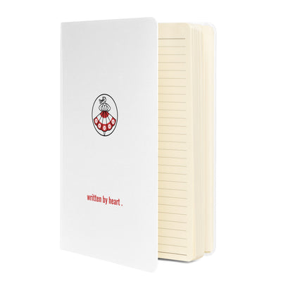 Vorderansicht des weißen Hardcover-Notizbuchs von POLCOUTURE. Auf dem Einband sind das Logo und der Slogan „written by heart“ zentral unten platziert. Minimalistisches, edles Design.