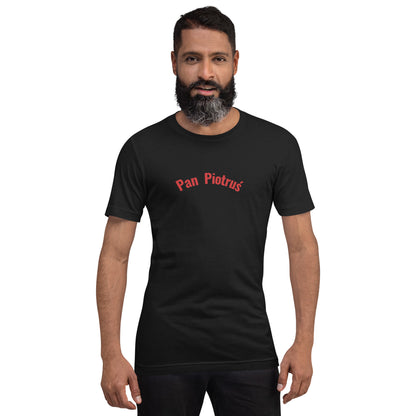 Frontalansicht eines Models in einem POLCOUTURE Unisex-T-Shirt in Vintage Schwarz. Zentriert auf der Brust ist der Schriftzug „Pan Piotruś“ in einer klaren, roten Schrift aufgedruckt.