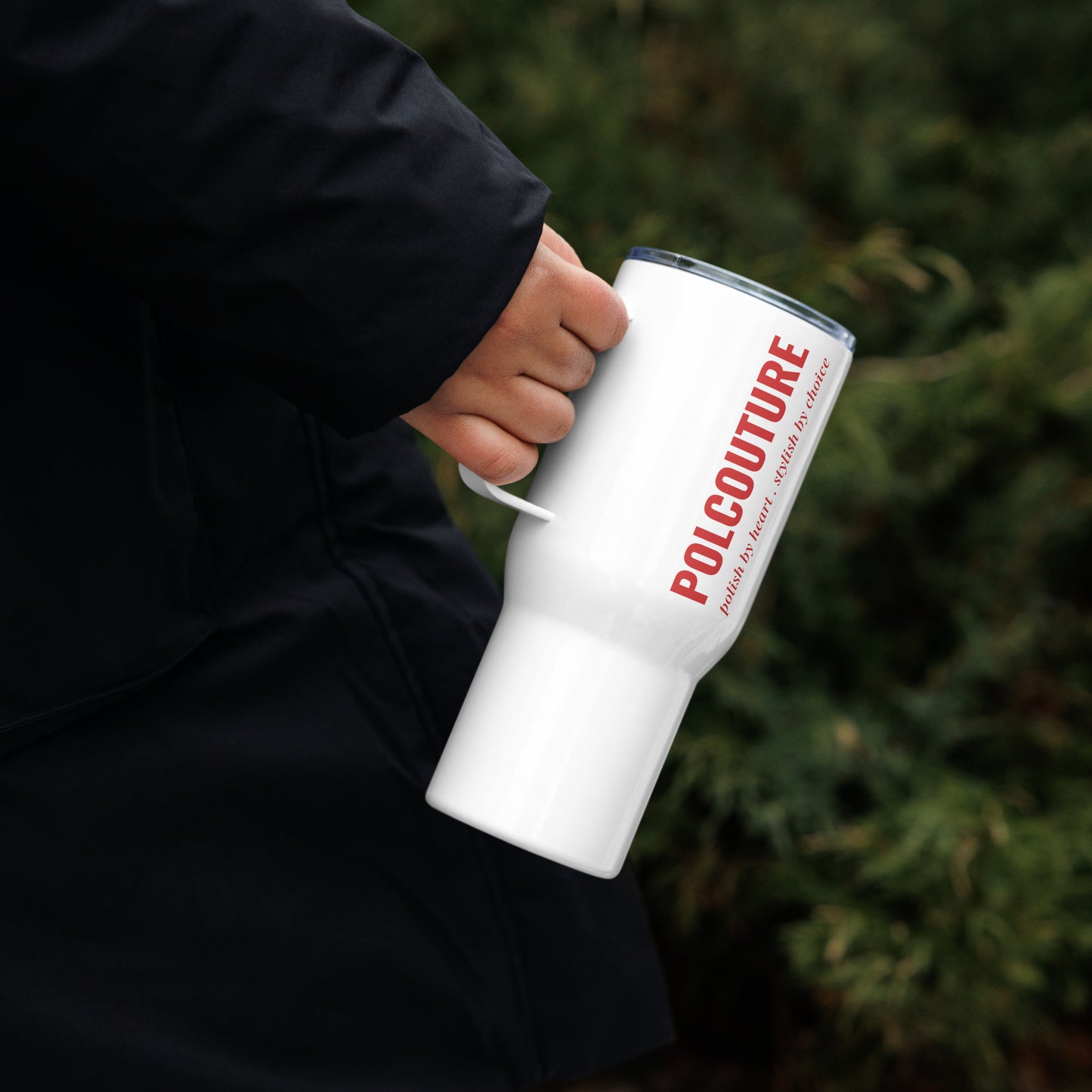 Person in schwarzem Hoodie hält den weißen Travel Mug „ŁYK“ von POLCOUTURE in der rechten Hand. Der Schriftzug POLCOUTURE ist erkennbar.